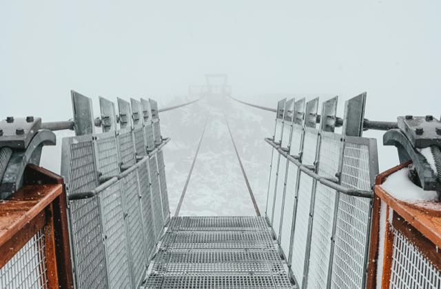 A very scary bridge across a chasm in the mist